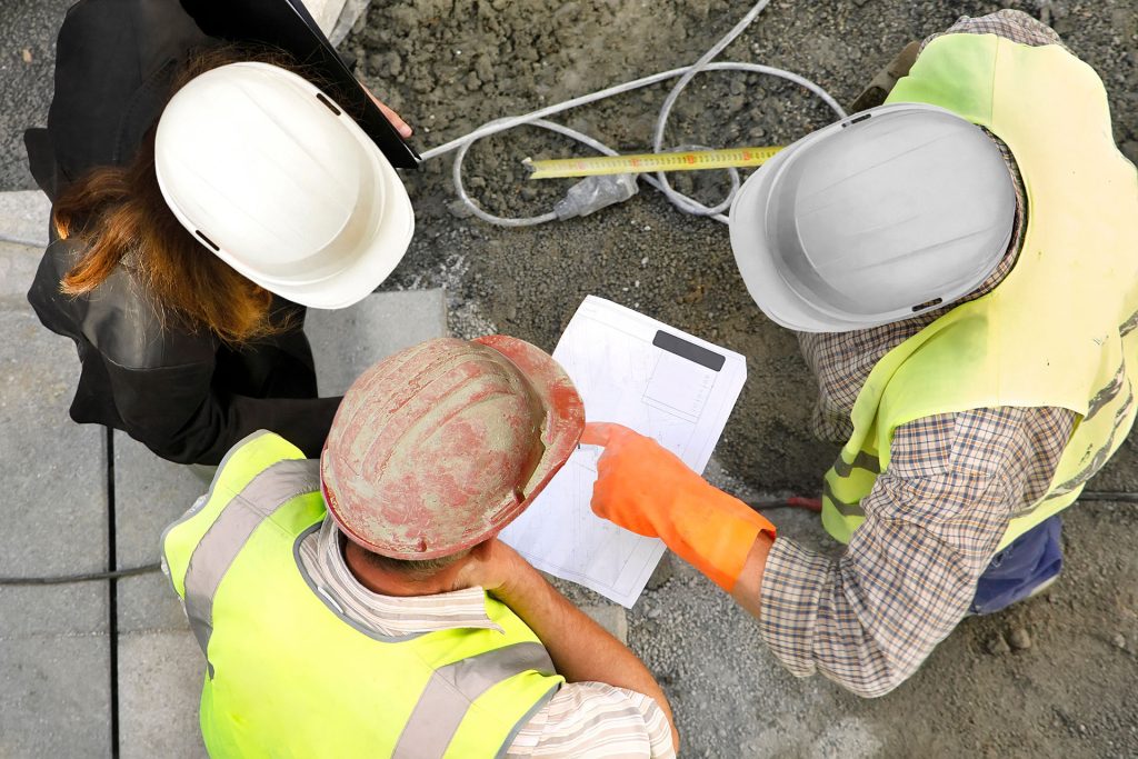 What is a site waste management plan? This image shows an aerial view of three people on a constuction site reviewing the site waste management plan