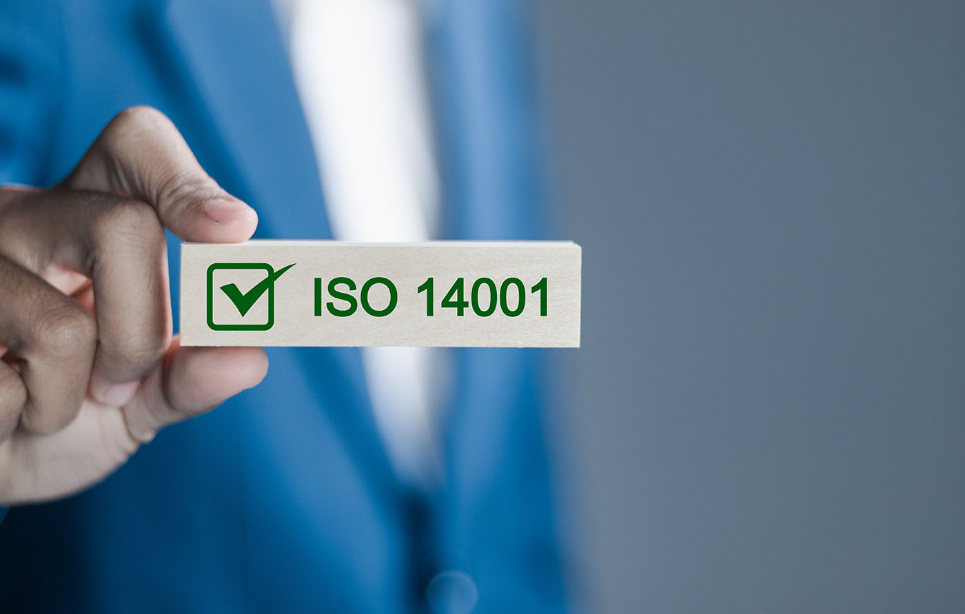 What is ISO 14001? This image shows a person in a blue blazer holding a block which says ISO 14001